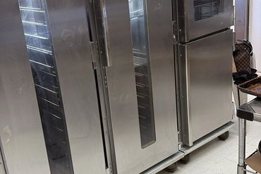 Commercial kitchen ovens with stainless steel doors and glass windows.