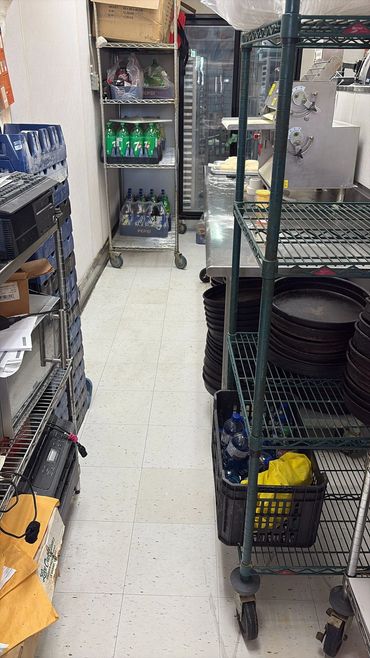 Kitchen storage area with shelves, soda bottles, and baking trays.