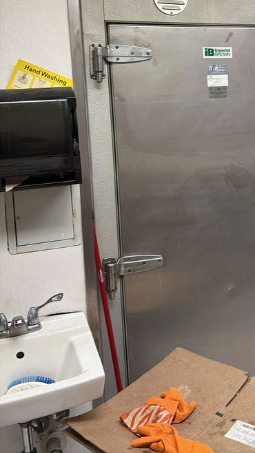 Industrial stainless steel door with cleaning supplies and sink nearby.