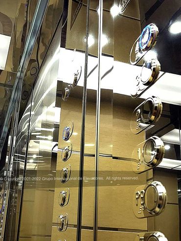 Detalle de un panel de control y su reflejo de un elevador de acero inoxidable acabado espejo dorado