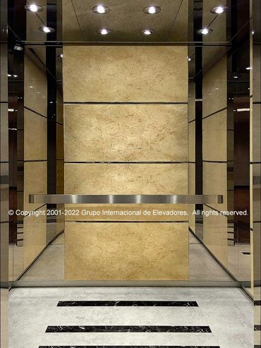 Vista frontal de un elevador de mármol sobre acero inoxidable acabado espejo.
