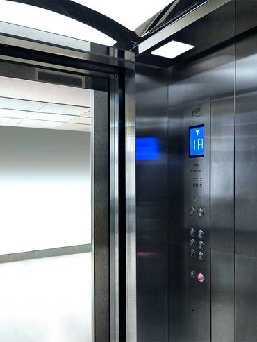 Elevador para pasajeros en acero inoxidable con las puertas abiertas en pasillo