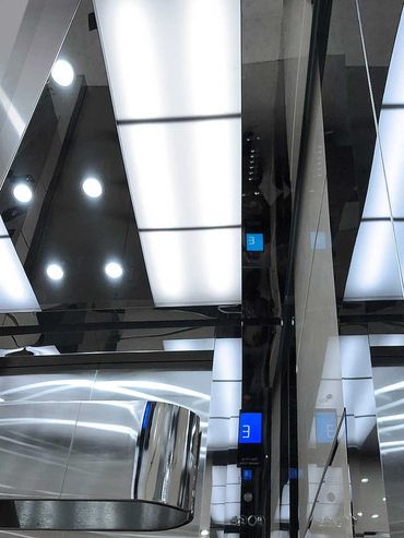 Detalle del pasamanos y reflejo del interior de un elevador para pasajeros