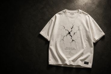 White t-shirt with a cracked design and motivational text on a dark background.