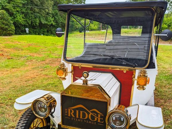 Vintage white and gold car branded with The Ridge Event Venue logo.