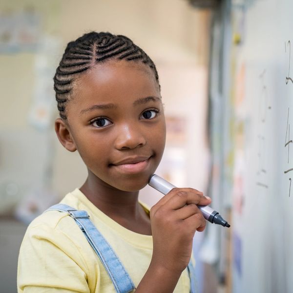 Young girl with braided hair holding a marker.