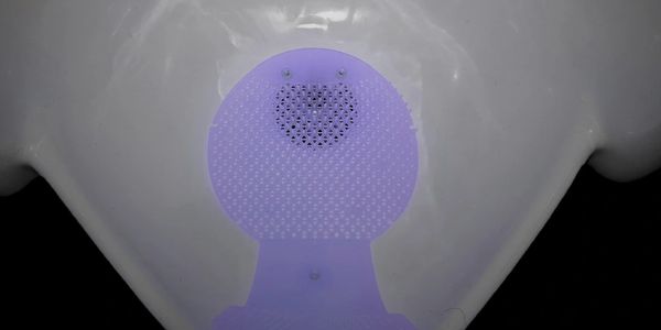 Patented U-R-IN urinal screen installed in a commercial washroom urinal