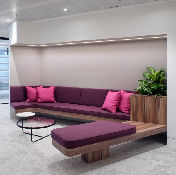 Modern seating area with purple cushions and green plants in a sleek, minimalist room.