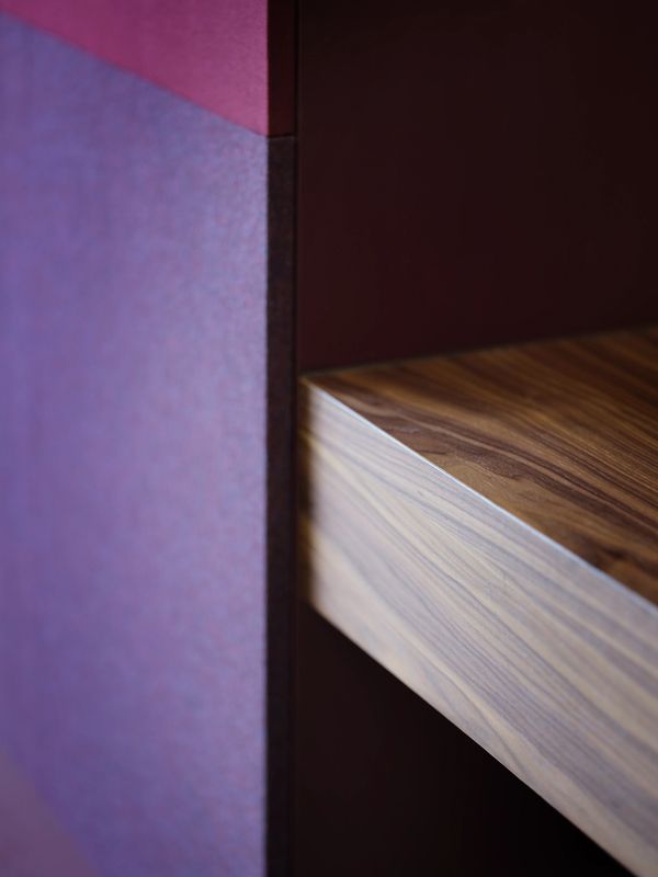 Close-up of a wooden shelf against a purple wall.