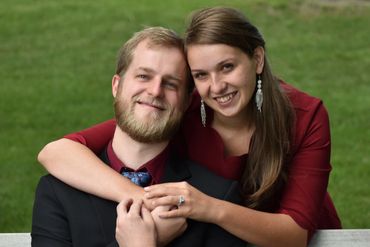 A happy couple embraces on a bench in a green park.