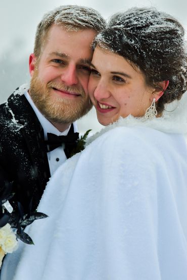 A happy couple embraces in the snow during their winter wedding.
