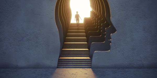 Person walking up steps shaped like a human head silhouette.