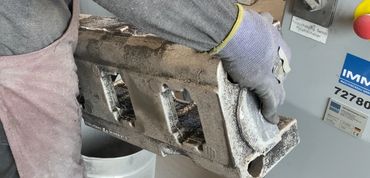 Aluminiumgussteil wird manuell an stationärer Bandschleifmaschine bearbeitet