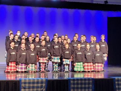 Group of performers in kilts on stage.
