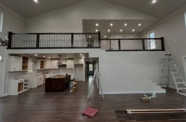 Spacious modern kitchen and living area under construction with dark wood flooring.