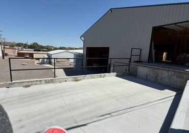 Concrete loading dock area with metal railing and warehouse building.
