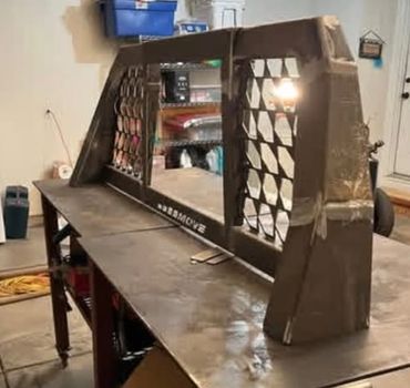 Custom metal truck headache rack with honeycomb design on a workbench.
