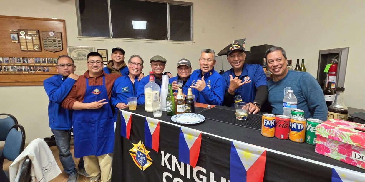 Group of men posing behind a Knights of Columbus bar with drinks.