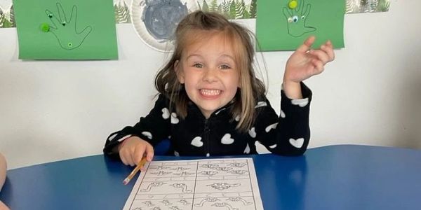 Happy girl doing a drawing activity at a table.
