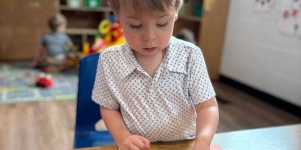 Young boy focused on a puzzle at a table.