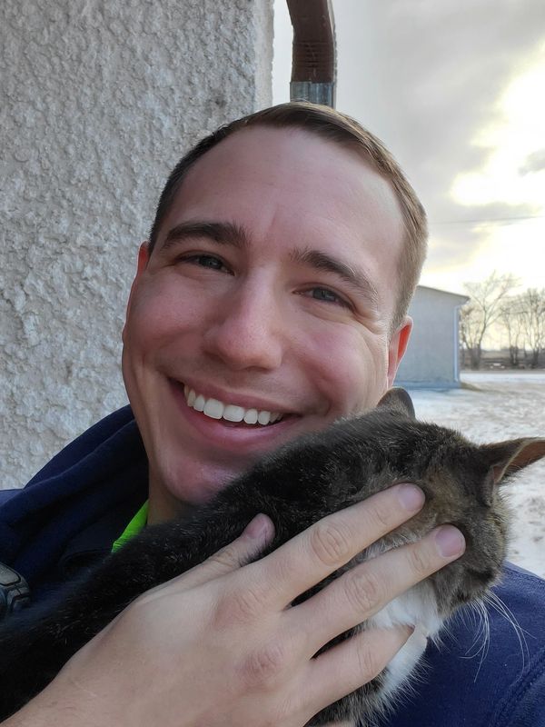 Photo of the author, London Berens, in winter. He is smiling and holding a rescued cat.