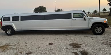 White stretch limo parked on gravel.