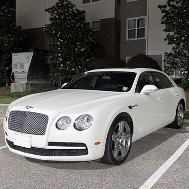White Bentley parked outside a Residence Inn at night.