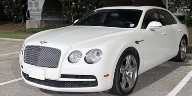 White luxury Bentley car parked outdoors.