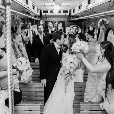 Wedding couple kissing with friends celebrating.