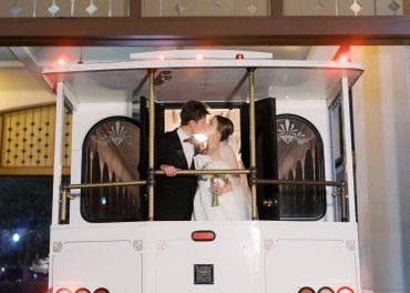 Newlyweds kiss on a trolley at night.