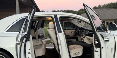Luxury white car with open doors showing beige leather interior.