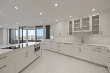 Modern white kitchen with island and city view.