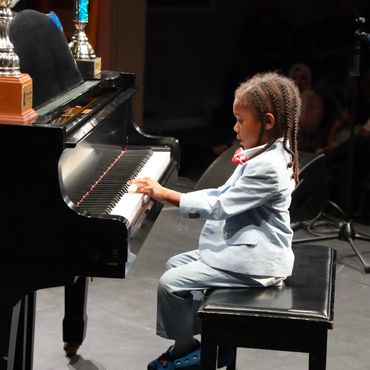 A young piano student performing at Cyril Clark Theatre with Synergy Music Academy