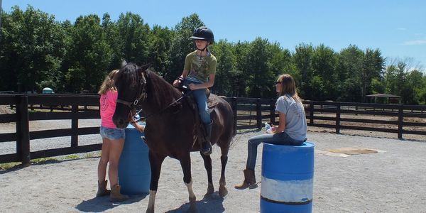 Riders jumping barrels outdoors.