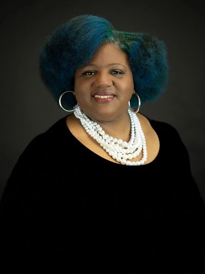 Portrait of a woman with blue hair and pearl necklace.