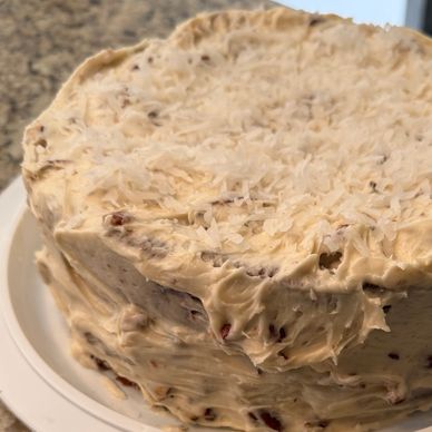 Homemade frosted cake with a textured creamy icing on a white plate.