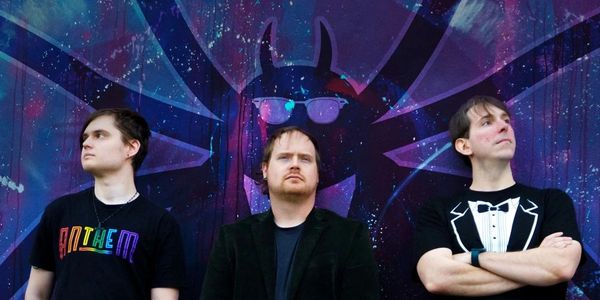 Three men standing in front of a graffiti wall.