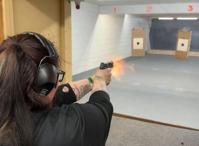 Person firing a handgun at an indoor shooting range.