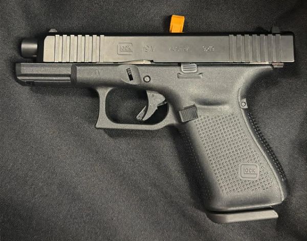 Black Glock 18C pistol on a dark surface.