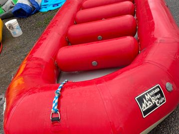 Red inflatable raft on gravel.
