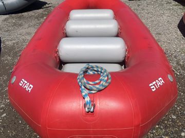 Red inflatable boat with rope on the ground.