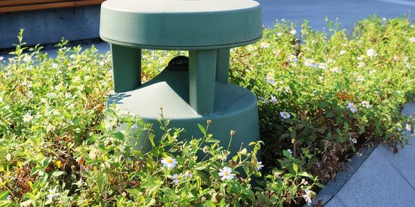 Green outdoor speaker among plants.
