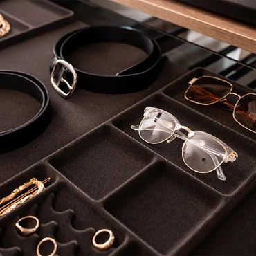 Organized tray with belts, glasses, and jewelry compartments.