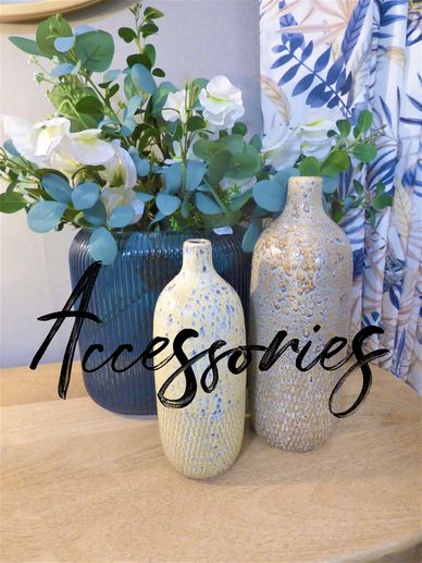 Large blue glass vase fully of white roses and eucalyptus with two ceramic mottled bottles