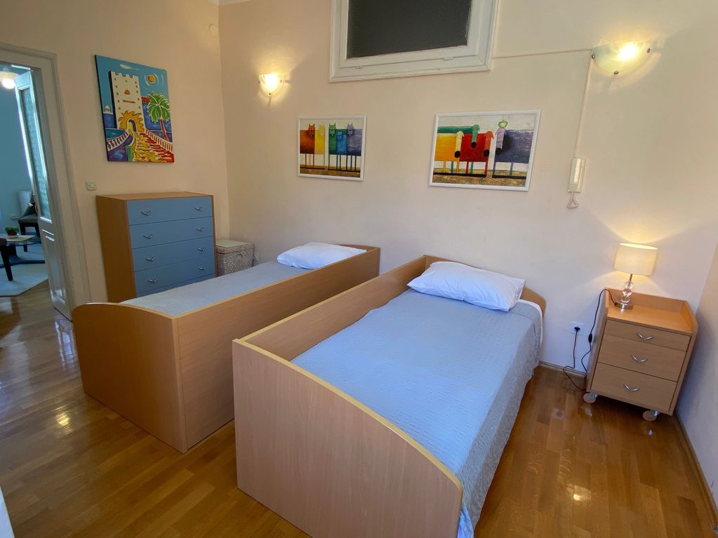 bedroom with 2 single beds, dresser, side table and nice colourful art