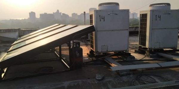 Solar panels and air conditioning units on a rooftop at sunset.