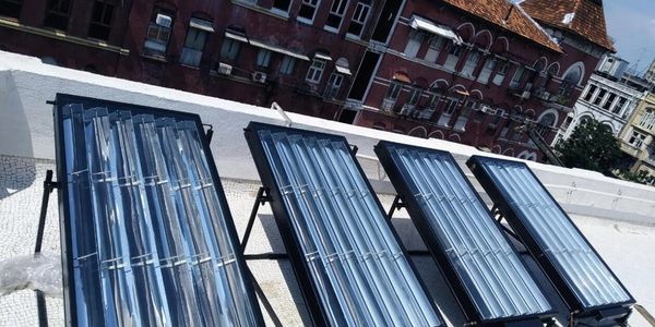 Four solar water heaters installed on a rooftop under clear sky.