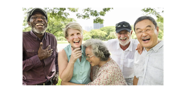 A diverse group of elderly friends laughing together outdoors.