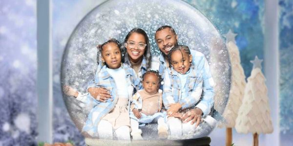 Family portrait inside a snow globe with winter decorations around.