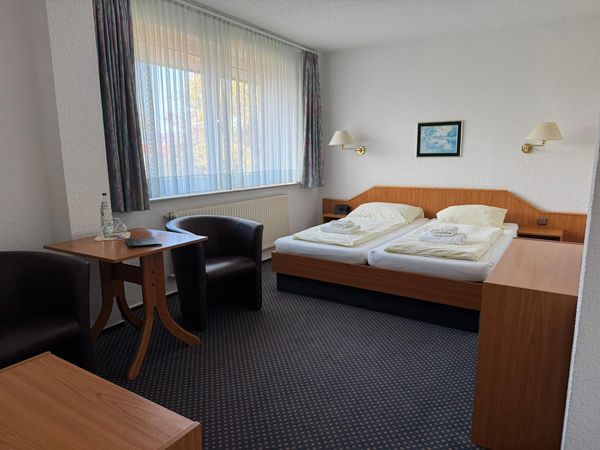 Sauberes Doppelzimmer mit zwei Betten und Tisch.